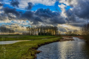 Helemaal in gedachten verzonken ben ik bijna ter plekke aangekomen. Ik kijk naar de foto en herken het brugje en de kronkelende kreek.